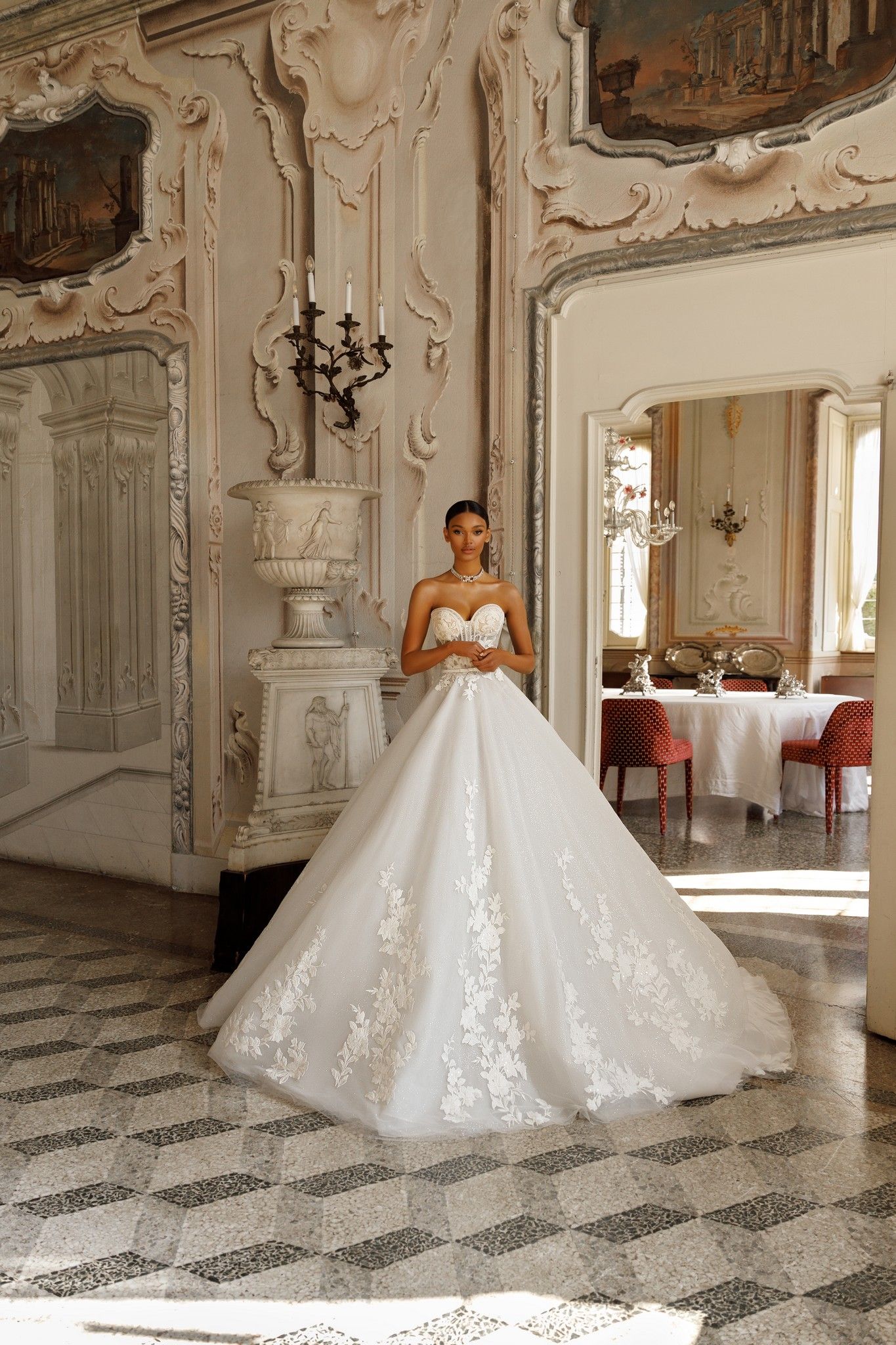 Eine Frau in einem Brautkleid steht in einem Raum vor einem Spiegel.