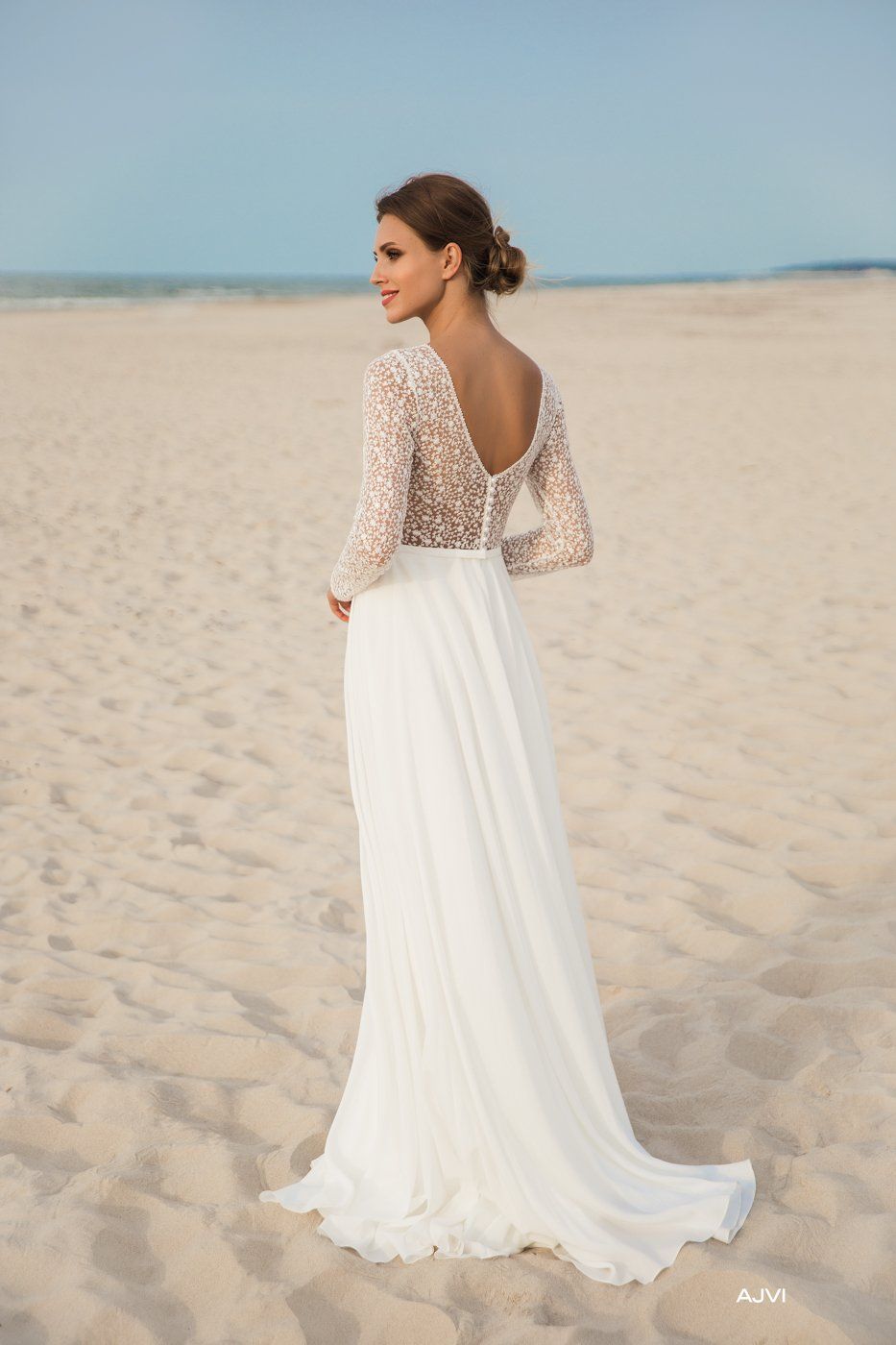 Eine Frau in einem weißen Brautkleid steht an einem Strand.