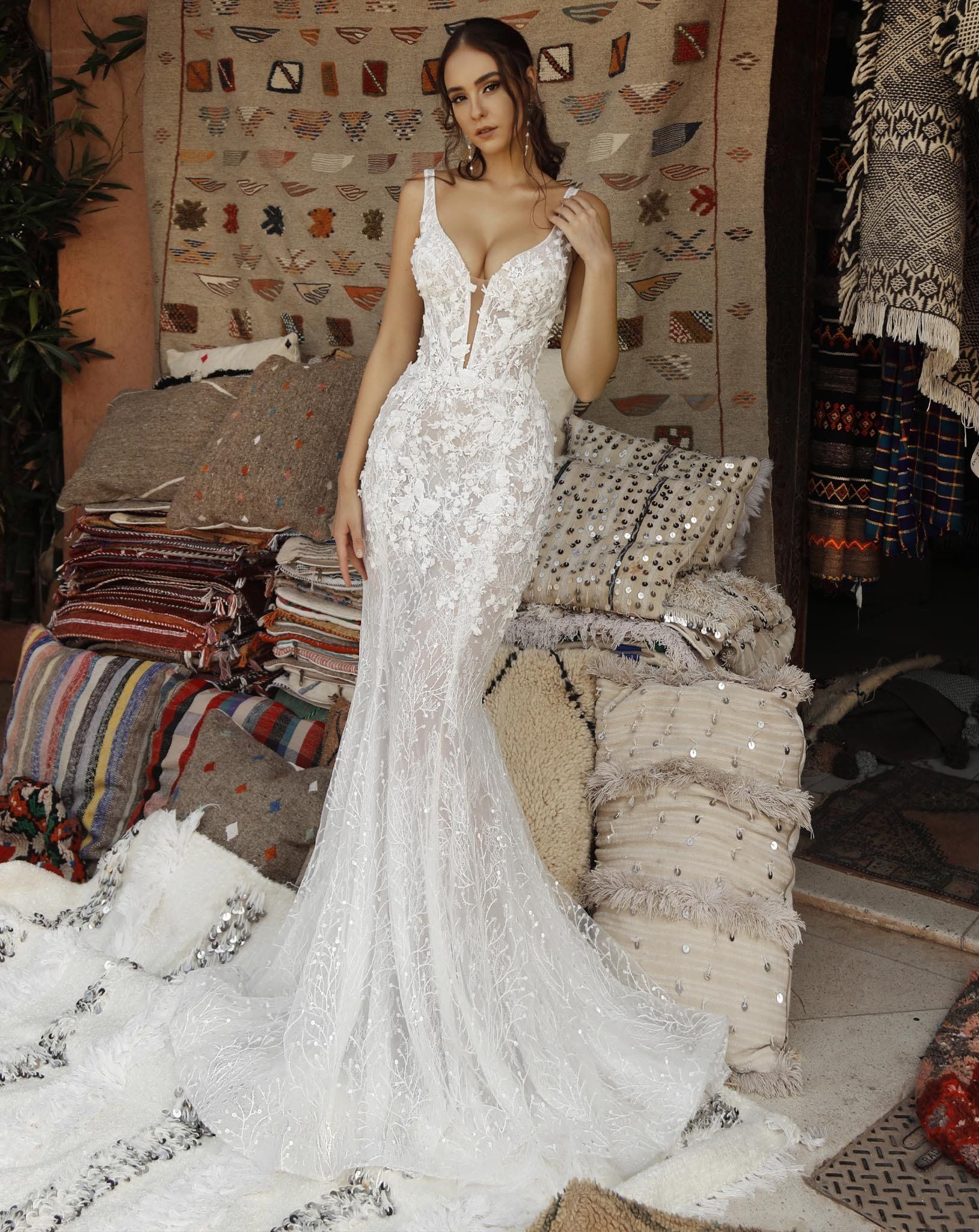 Eine Frau in einem weißen Brautkleid steht vor einem Stapel Kissen.