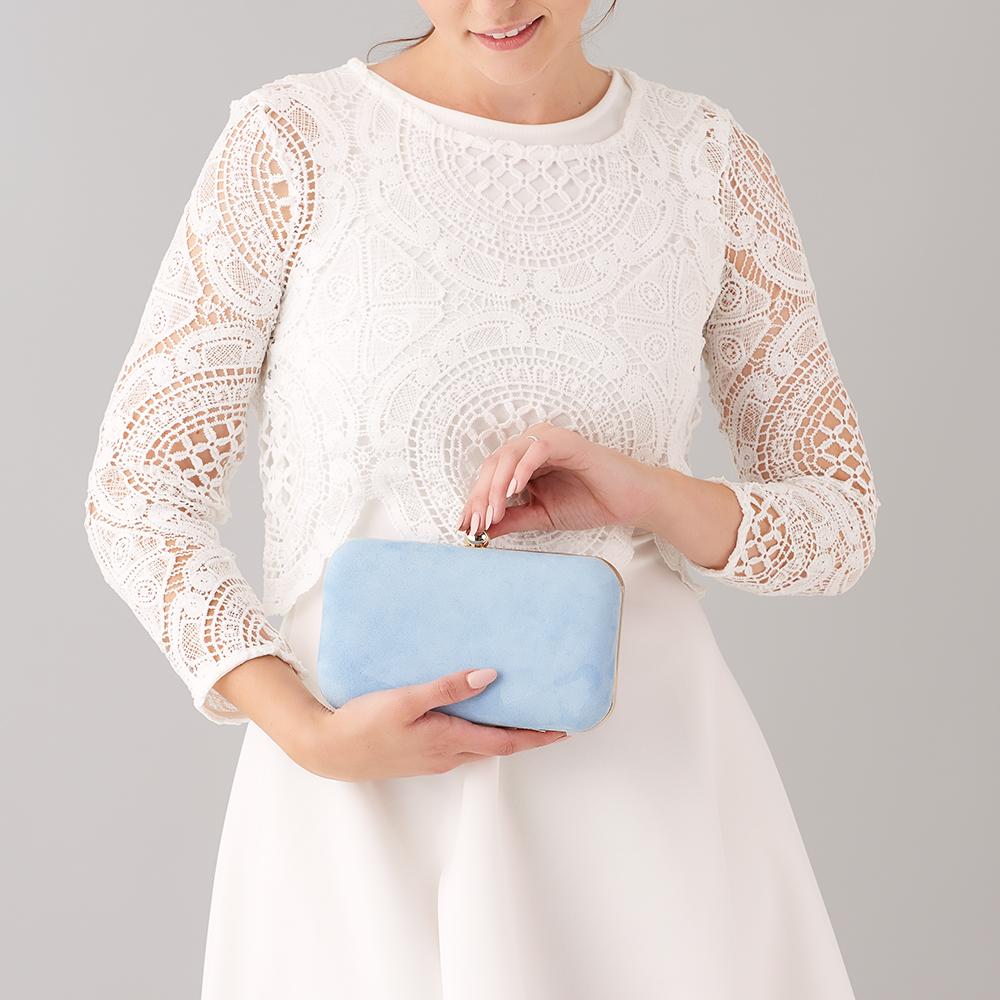 Eine Frau in einem weißen Kleid hält eine hellblaue Clutch.