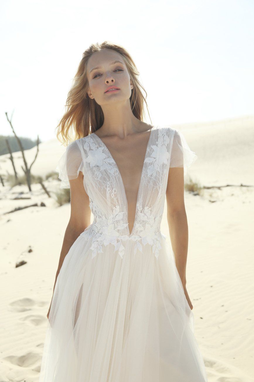 Eine Frau in einem Brautkleid steht im Sand.