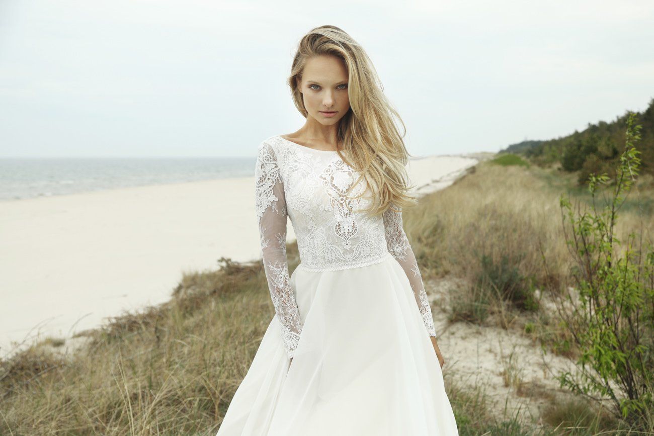 Eine Frau in einem Brautkleid steht an einem Strand.