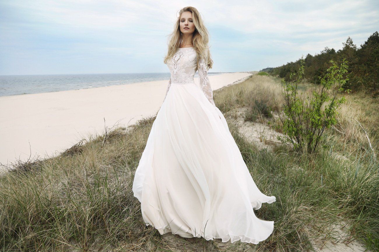 Eine Frau in einem Brautkleid steht an einem Strand.