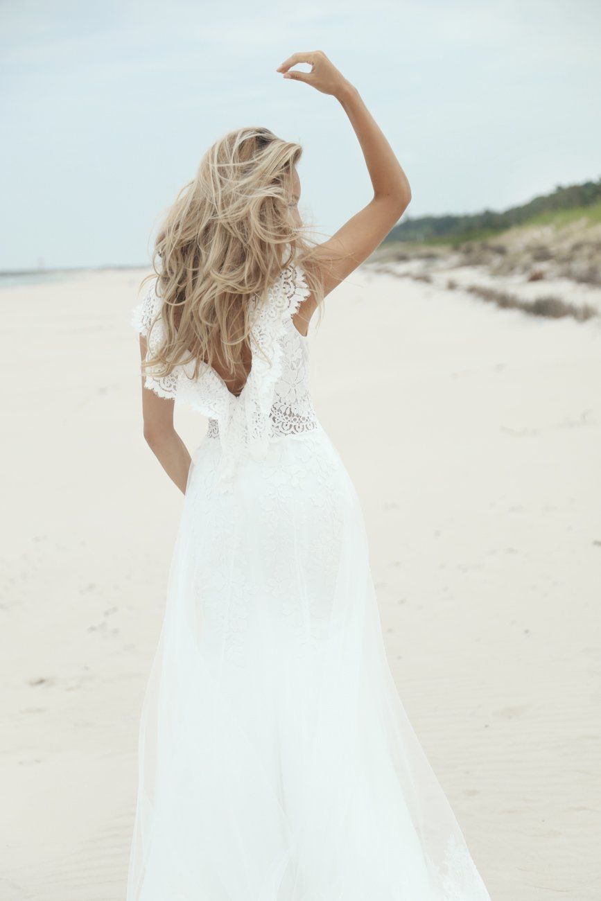 Eine Frau in einem weißen Kleid steht an einem Strand.