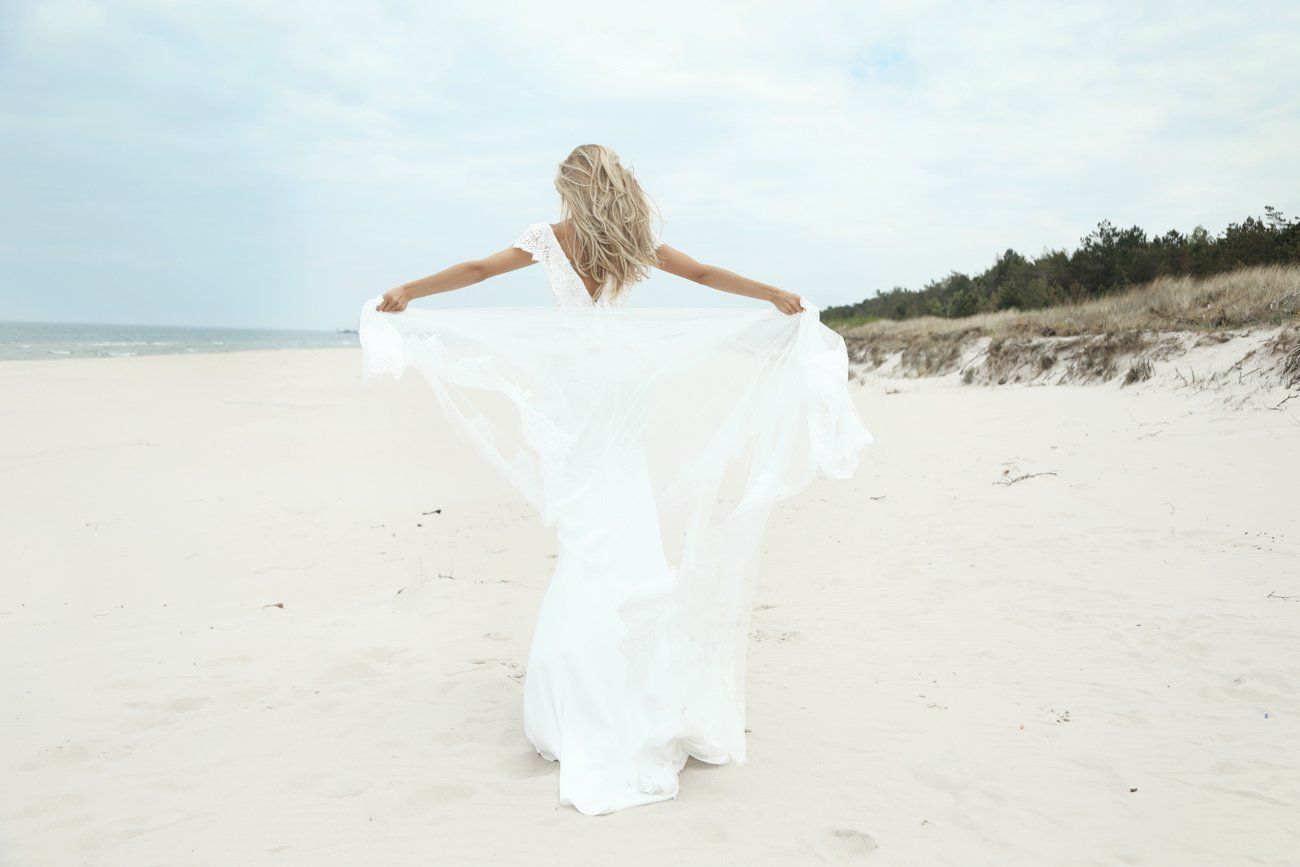 Eine Frau in einem weißen Kleid steht an einem Strand.