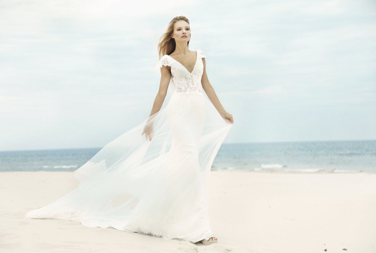 Eine Frau in einem Brautkleid steht an einem Strand.