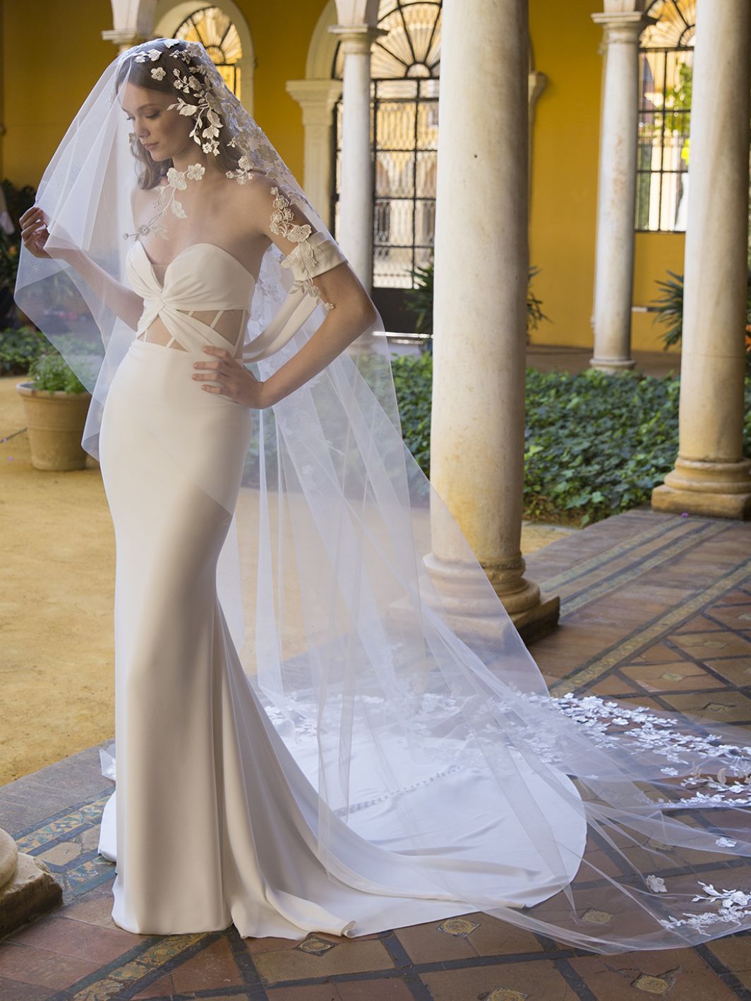 Eine Frau in einem Brautkleid und Schleier steht in einem Innenhof.