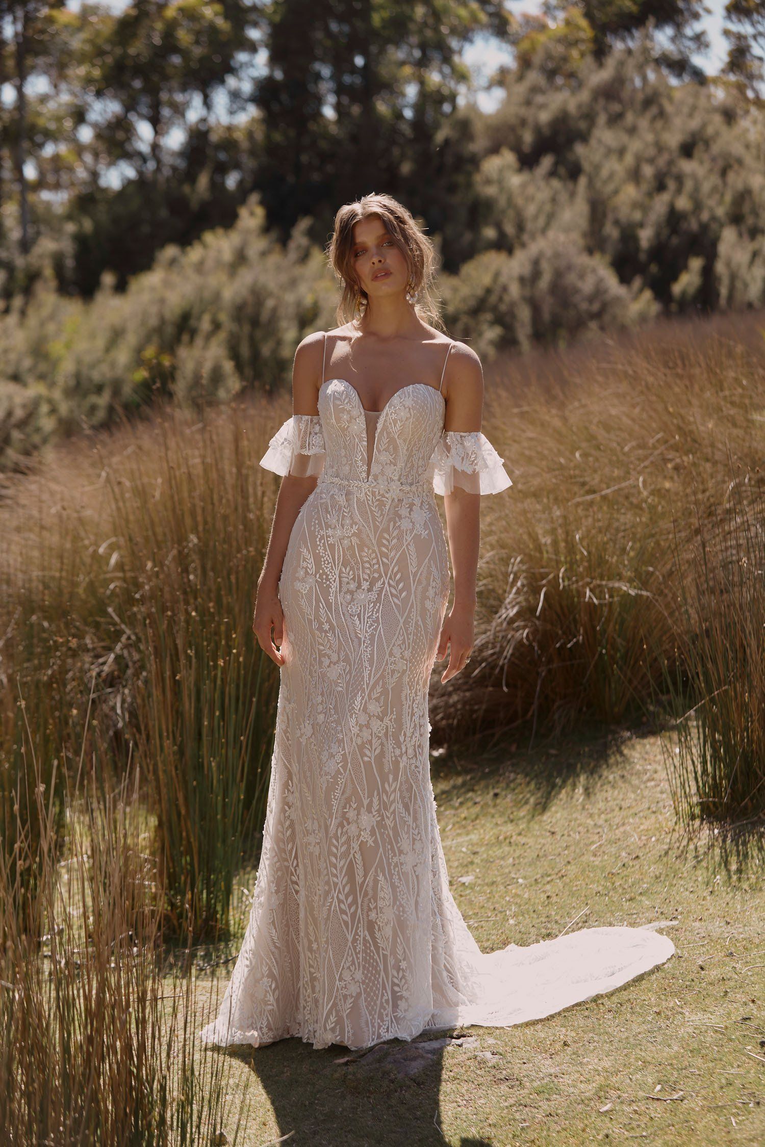 Eine Frau in einem Brautkleid steht auf einem Feld.