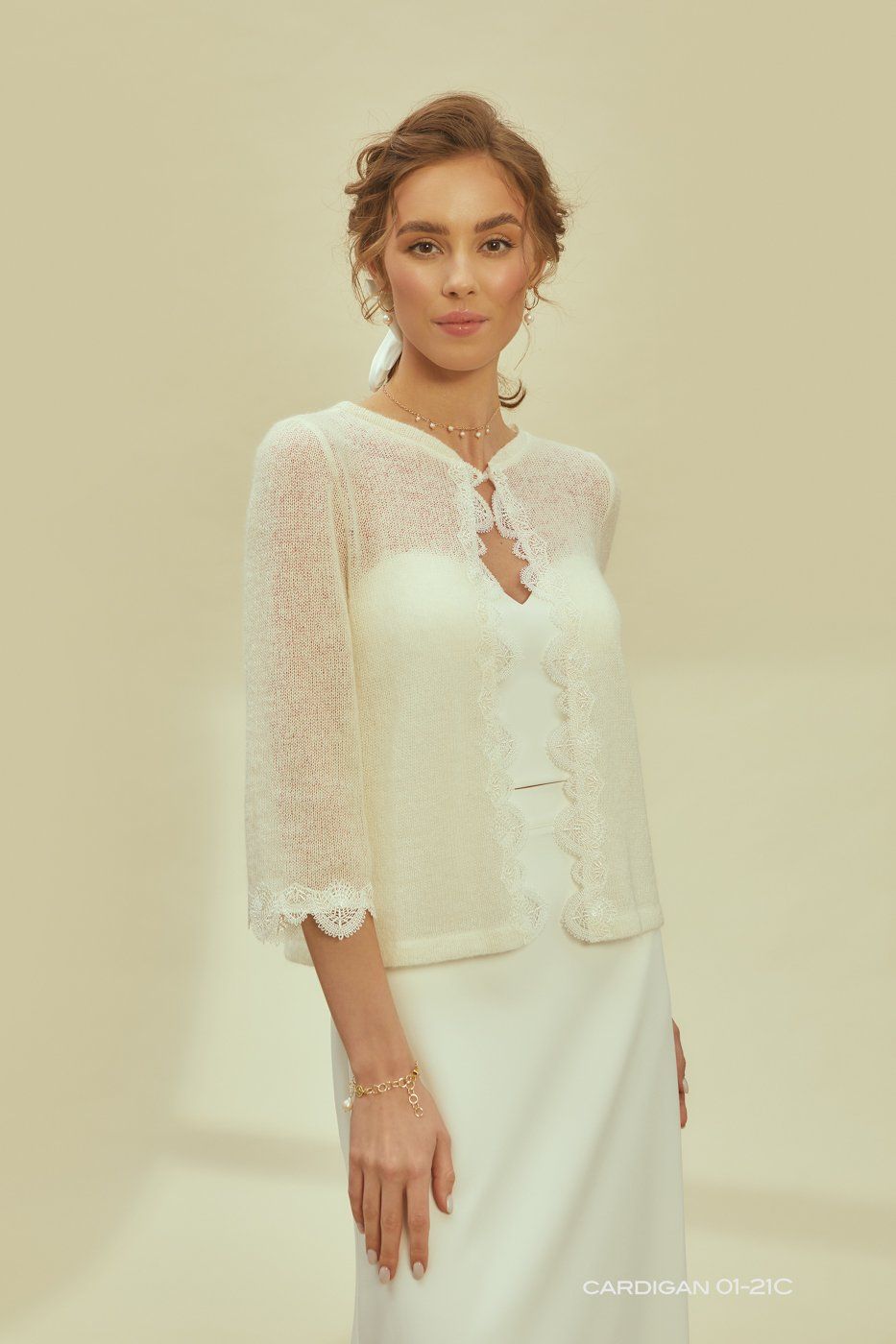 Eine Frau in einem Brautkleid trägt eine weiße Spitzenjacke.