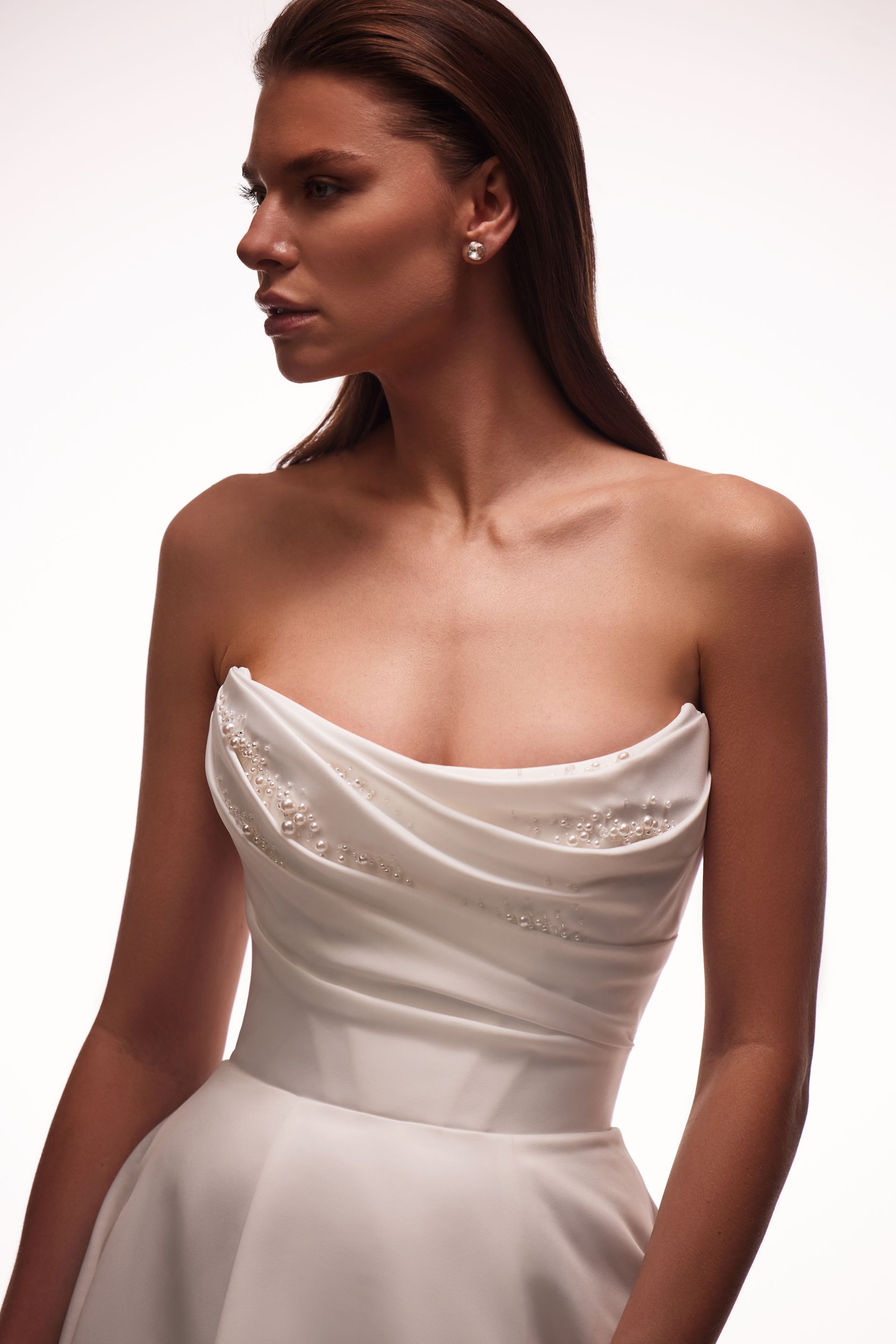 Eine Frau trägt ein weißes trägerloses Kleid und Ohrringe.