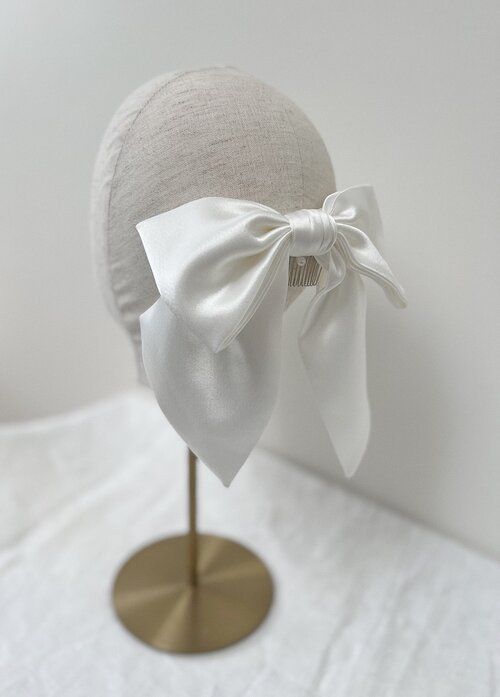 Auf dem Kopf einer Schaufensterpuppe sitzt eine weiße Schleife.