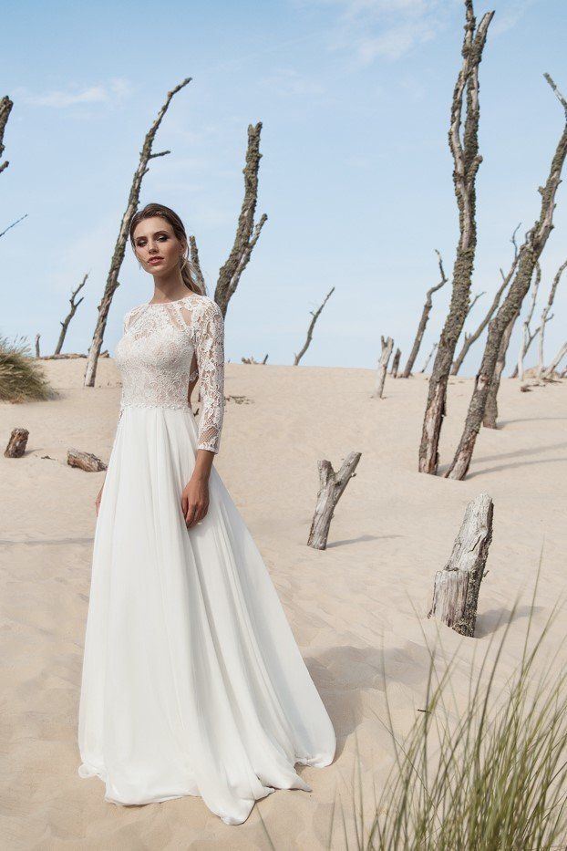 Eine Frau in einem weißen Brautkleid steht mitten in einer Wüste.