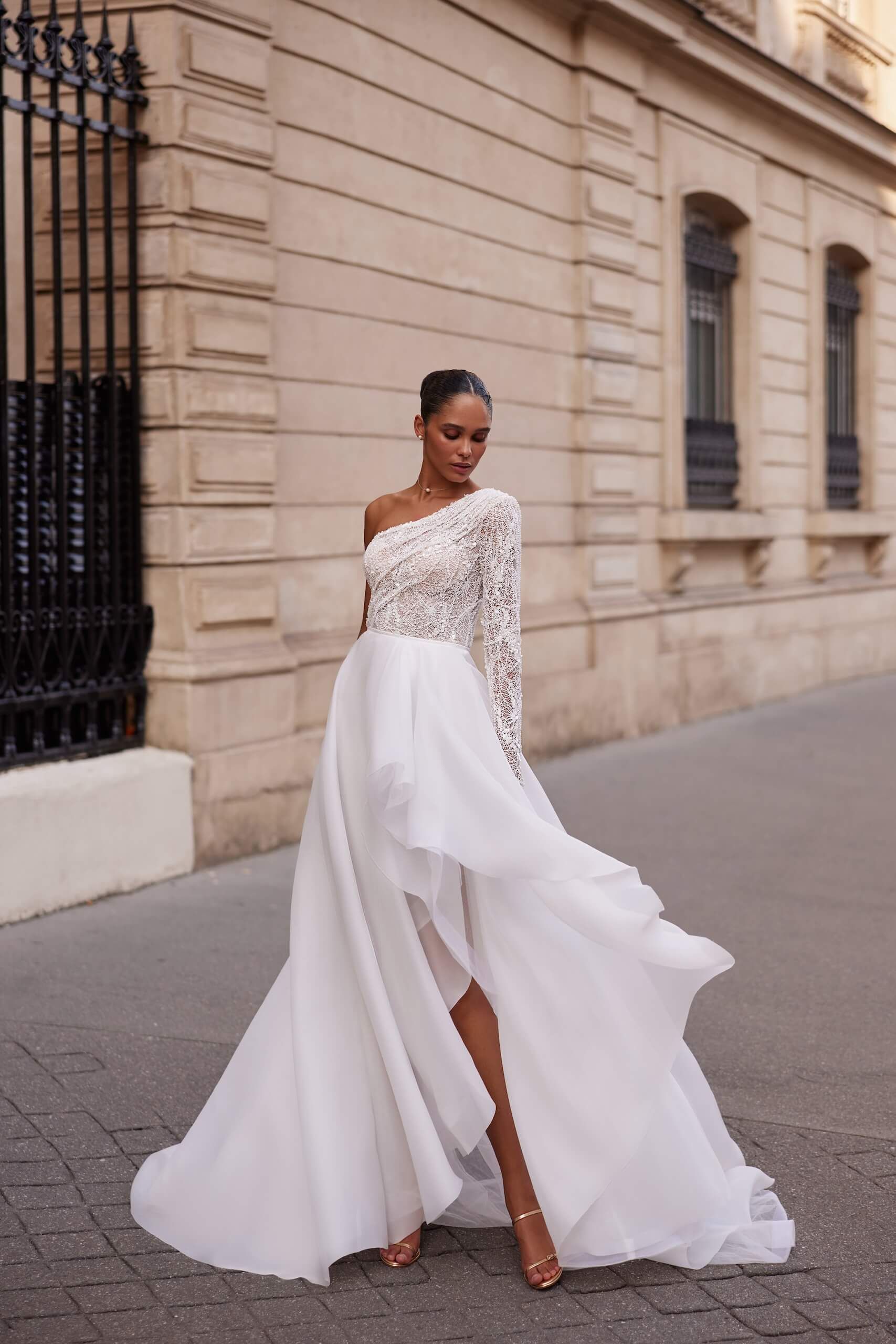 Eine Frau in einem weißen Brautkleid steht vor einem Gebäude.