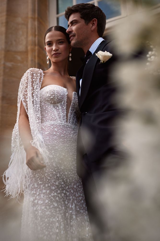 Eine Braut und ein Bräutigam stehen nebeneinander vor einem Gebäude.