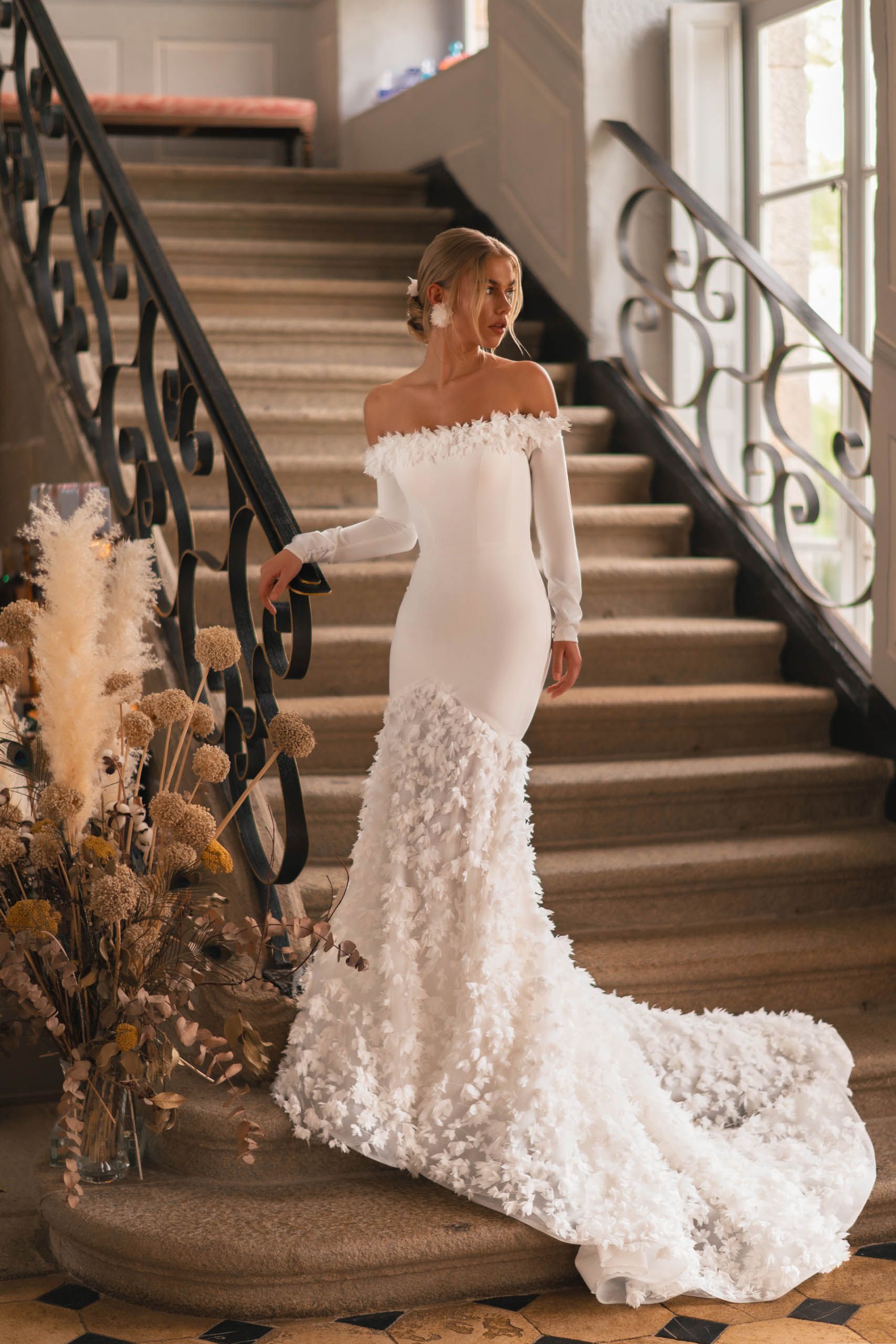 Eine Frau in einem weißen Brautkleid steht auf einer Treppe.