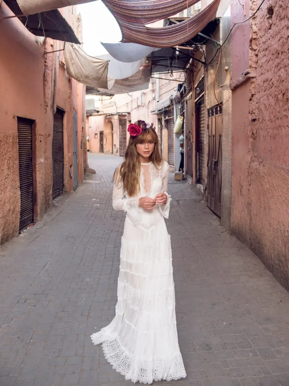 Eine Frau in einem weißen Kleid steht in einer engen Gasse.