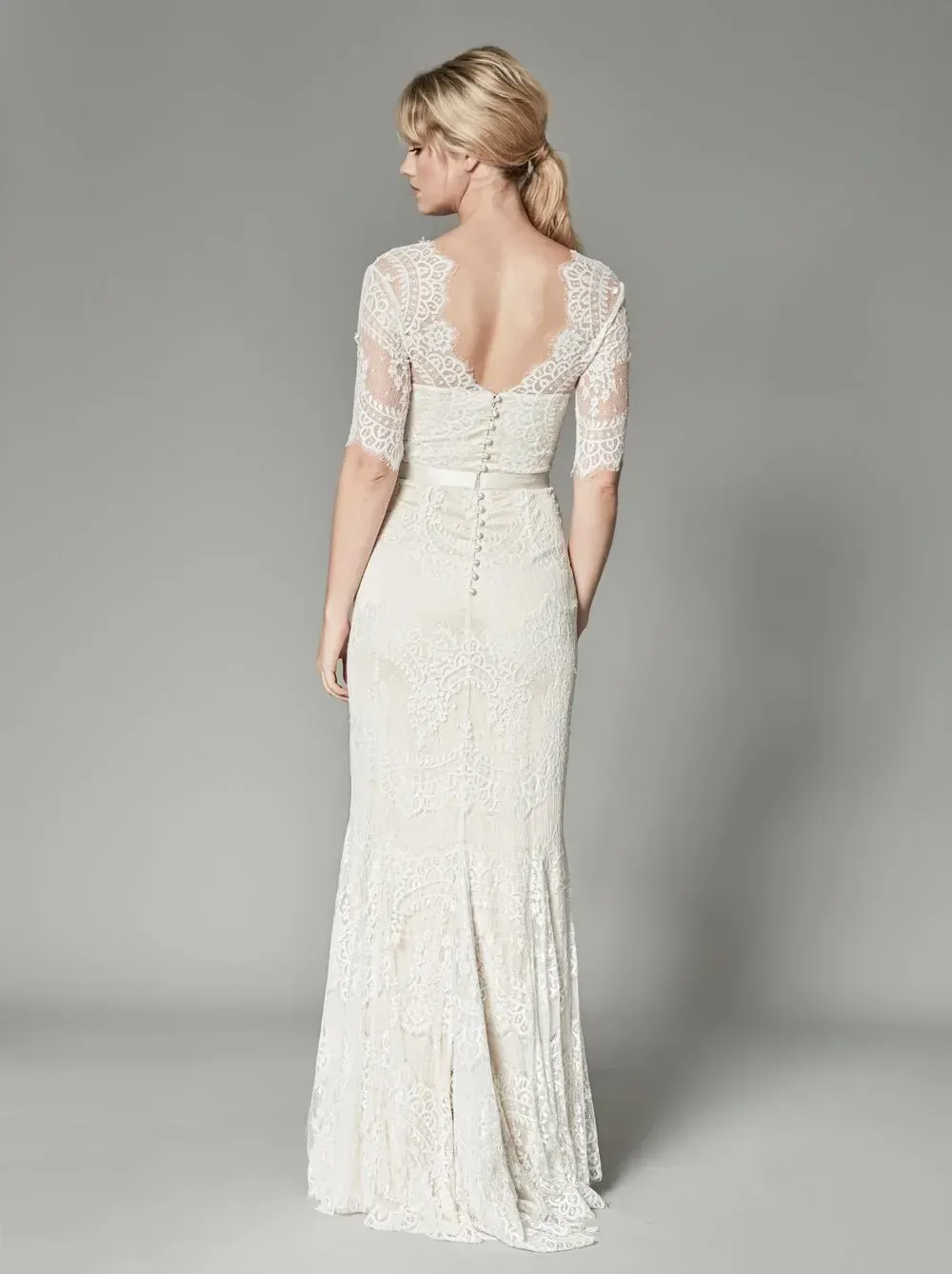 Der Rücken einer Frau, die ein weißes Spitzenbrautkleid trägt.