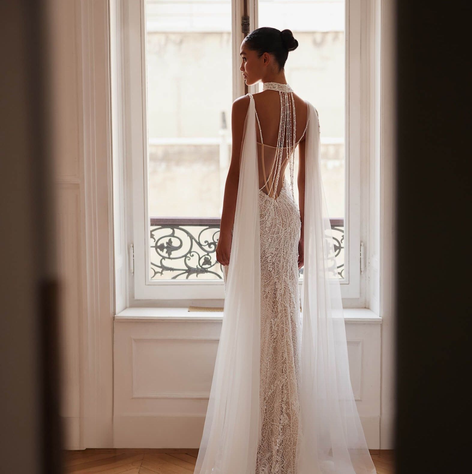 Eine Frau in einem weißen Kleid steht vor einem Fenster
