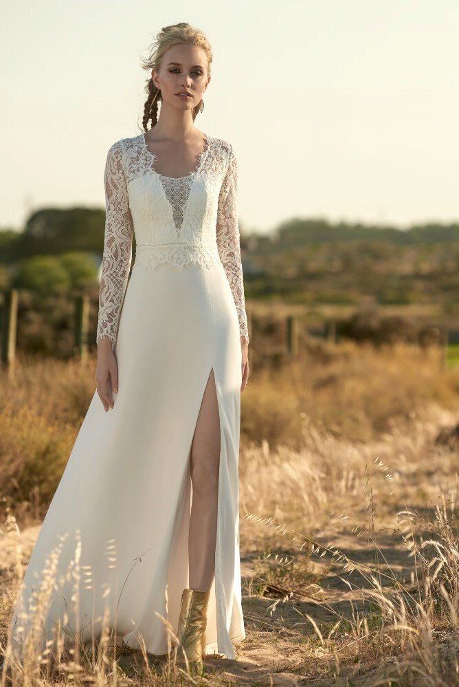 Eine Frau in einem weißen Brautkleid steht auf einem Feld.