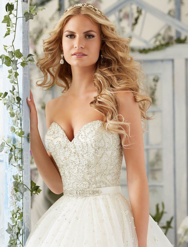 Eine Frau in einem Brautkleid lehnt an einer Wand.