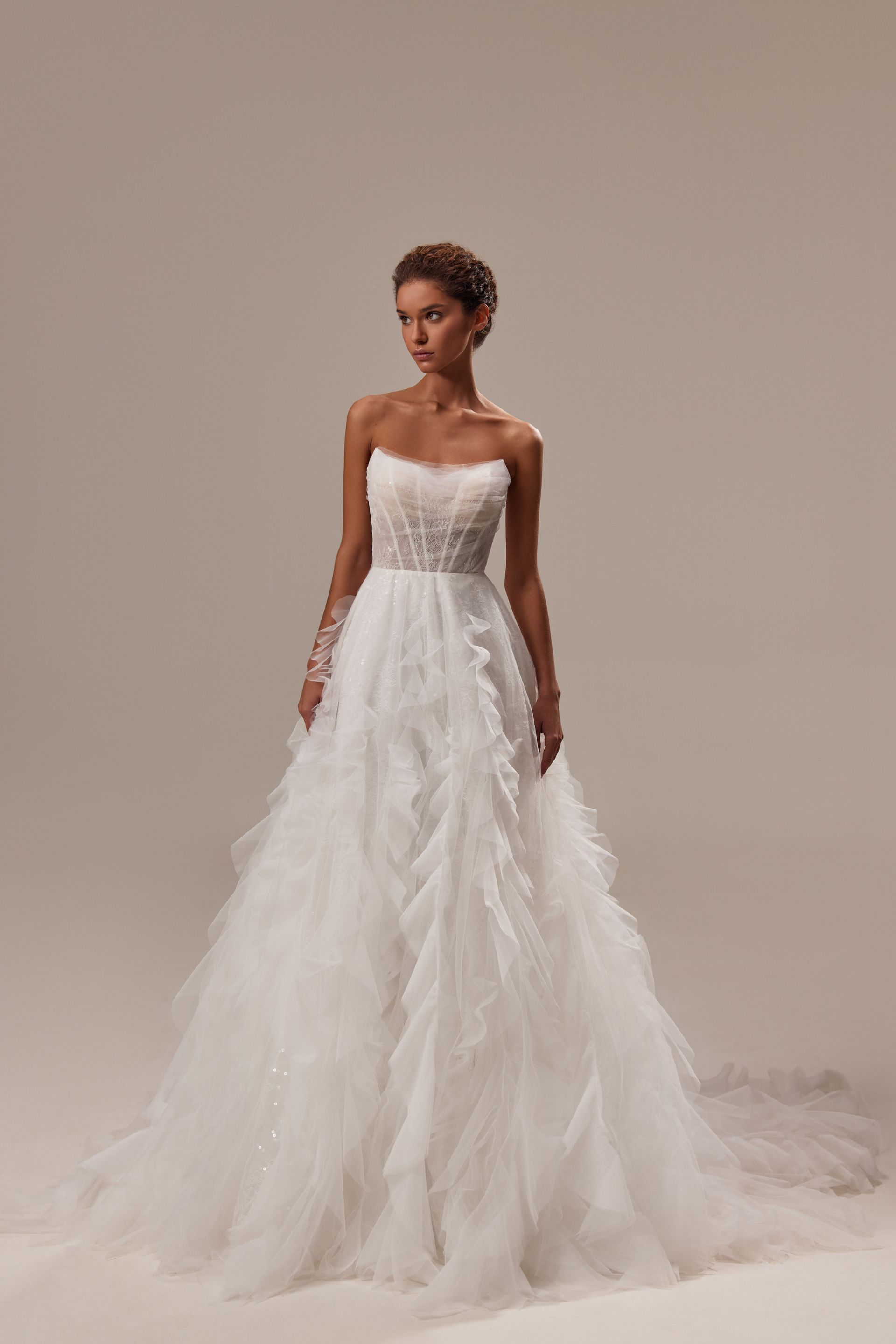 Eine Frau in einem weißen Brautkleid steht auf einer weißen Fläche.