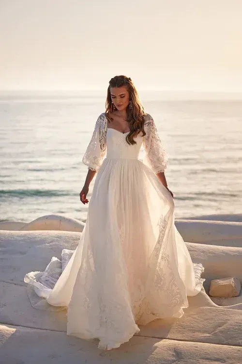 Eine Frau in einem weißen Brautkleid steht an einem Strand.