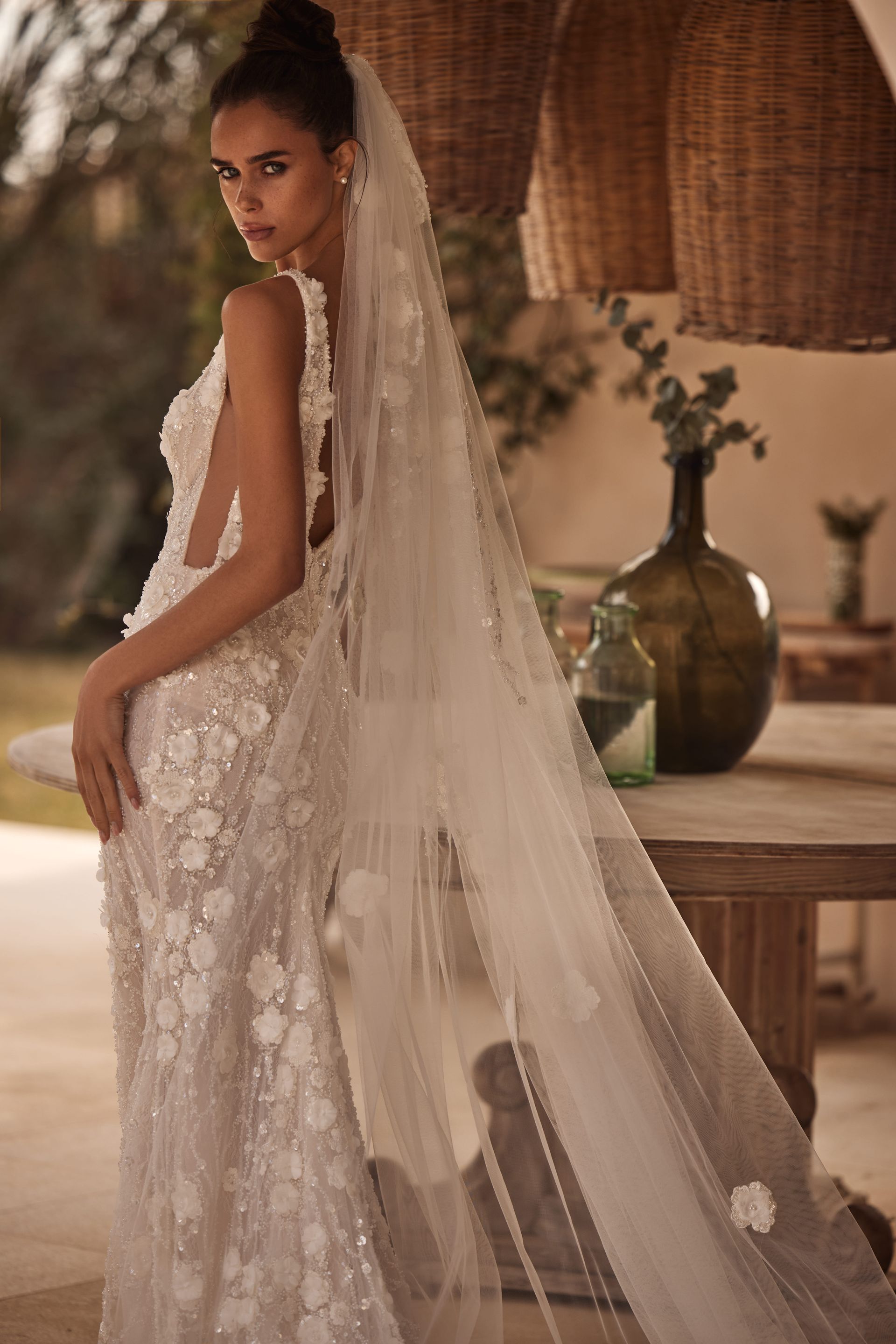 Eine Frau in einem Brautkleid und Schleier steht neben einem Tisch.