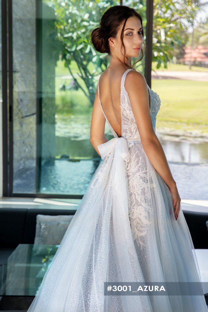 Eine Frau in einem Brautkleid steht vor einem Fenster.