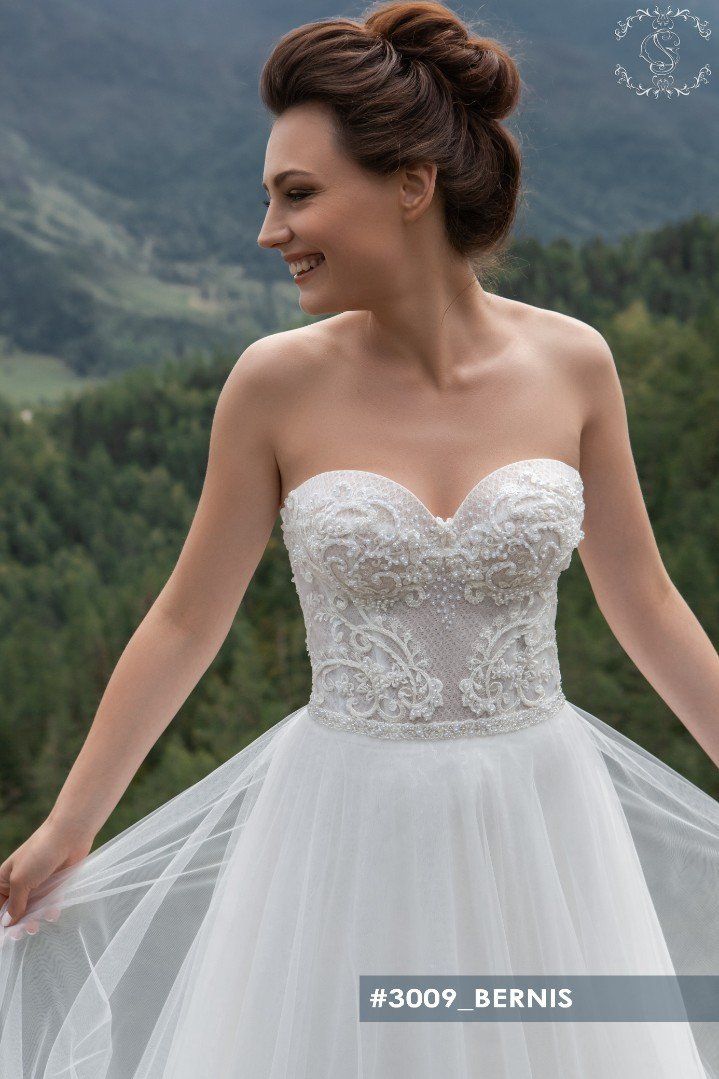 Eine Frau in einem weißen Brautkleid steht vor einem Berg.