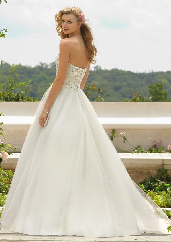 Eine Frau in einem weißen Brautkleid steht auf einer Bank.