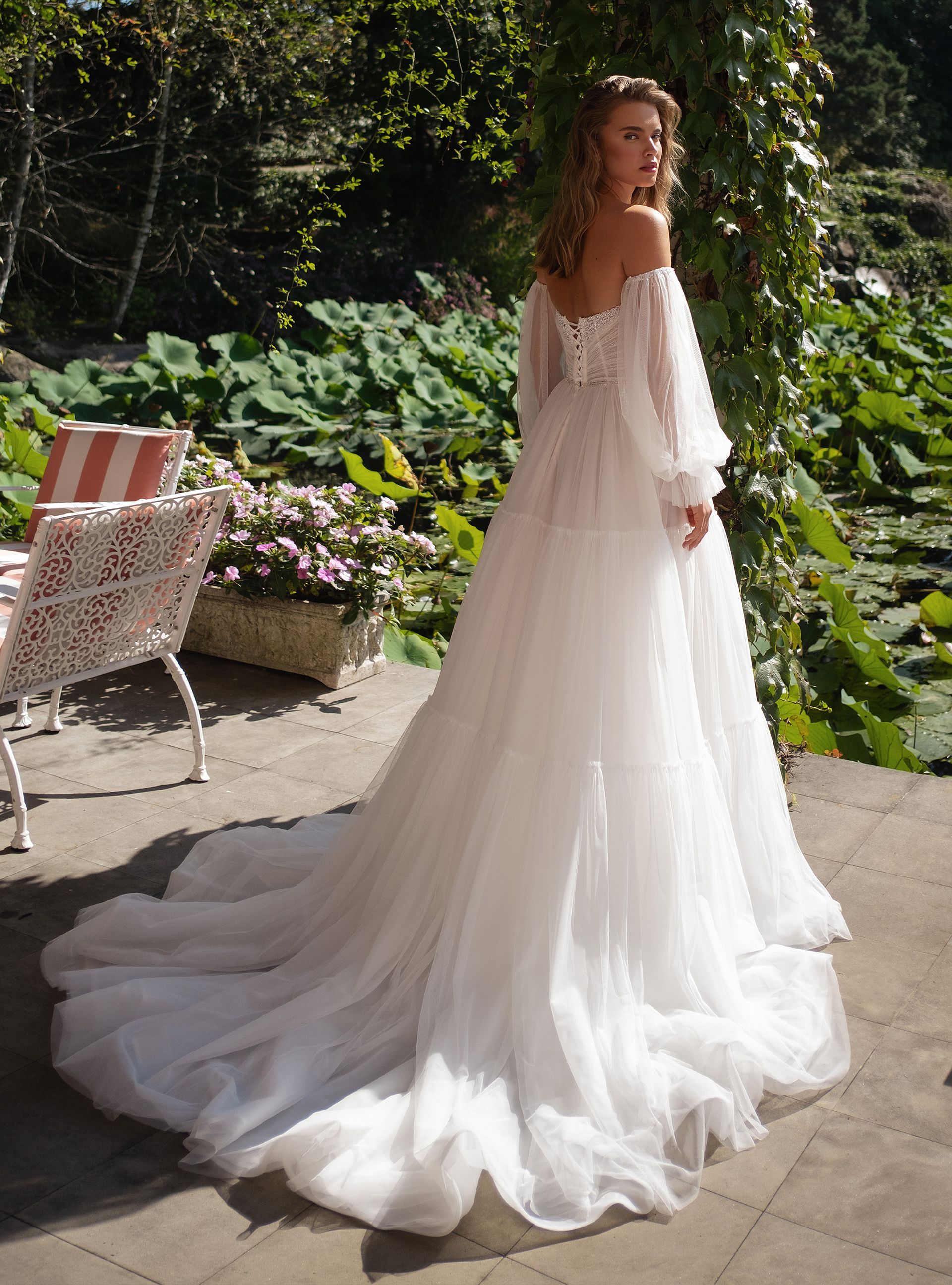 Eine Frau in einem weißen Brautkleid steht vor einem Teich.