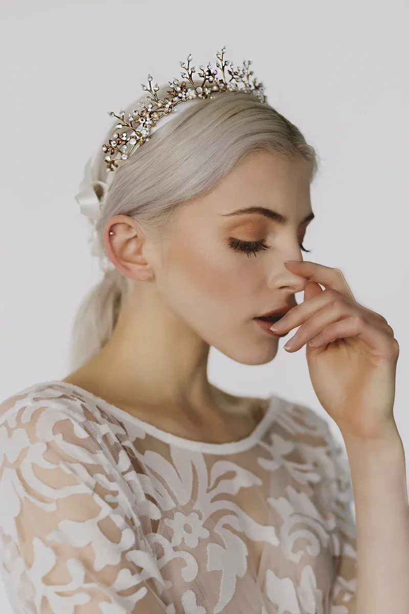 Eine Frau in einem weißen Kleid trägt eine Tiara auf dem Kopf.