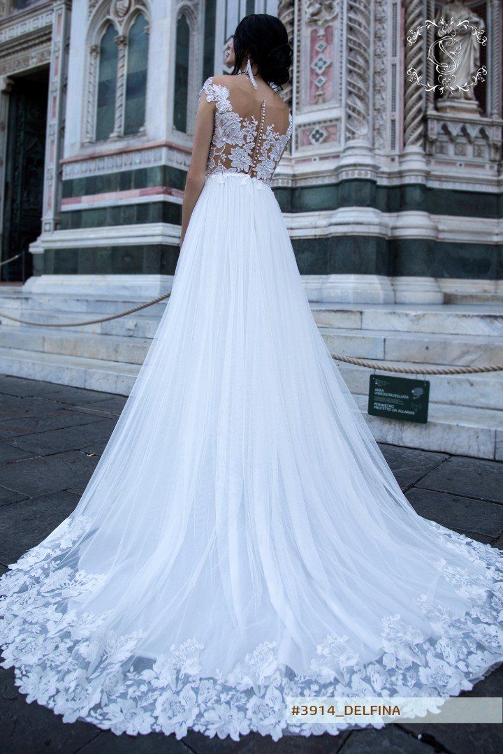 Eine Frau in einem weißen Brautkleid steht vor einem Gebäude.
