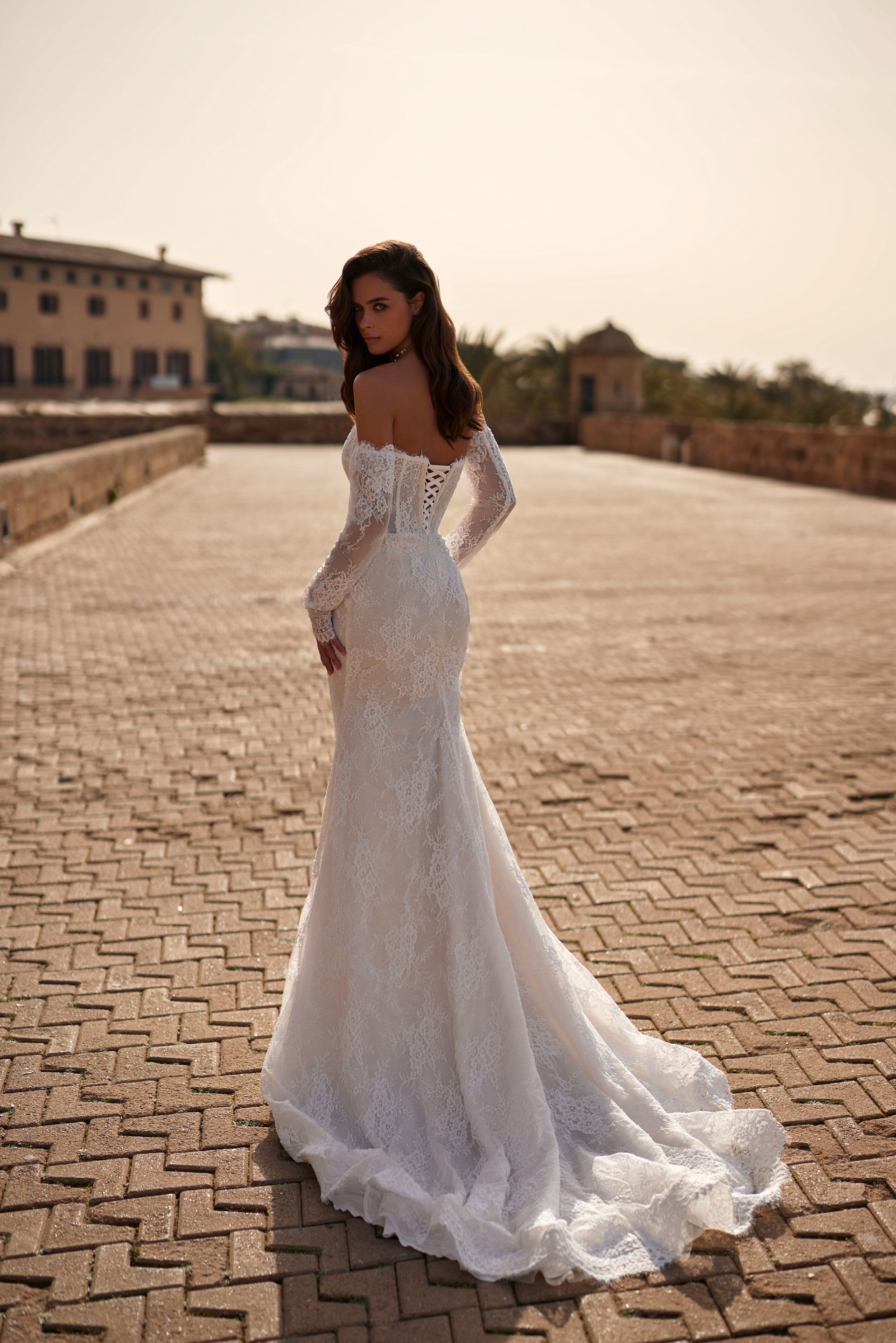 Eine Frau in einem Brautkleid steht auf einer Ziegelsteinstraße.