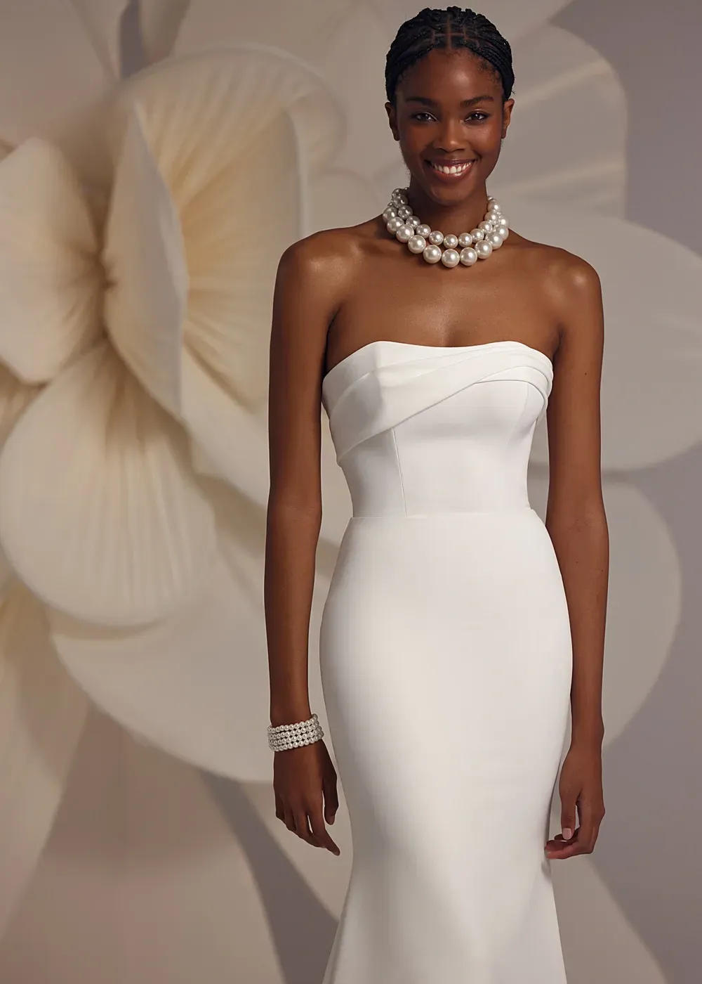 Eine Frau in einem weißen trägerlosen Kleid mit einer Perlenkette