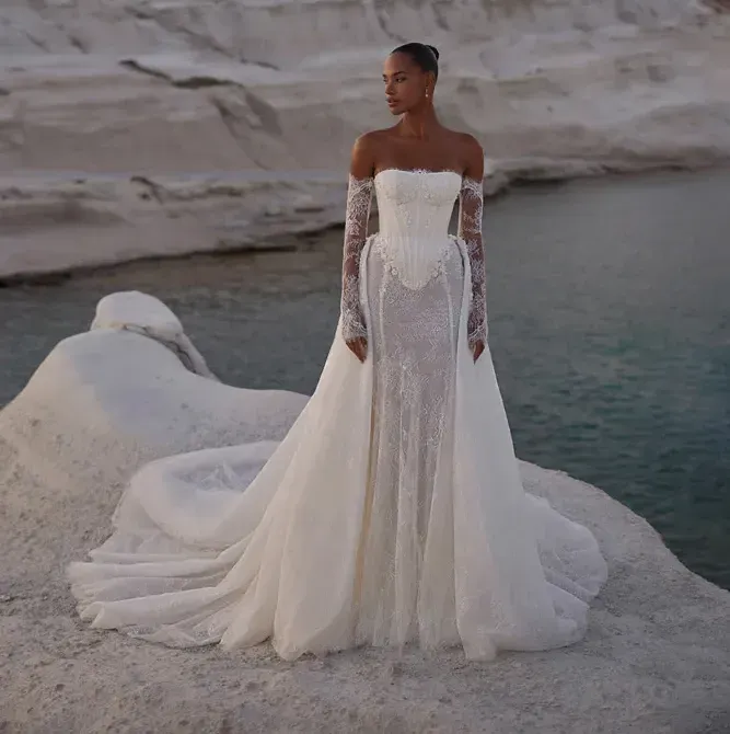 Eine Frau in einem weißen Brautkleid steht auf einem Felsen in der Nähe des Wassers.