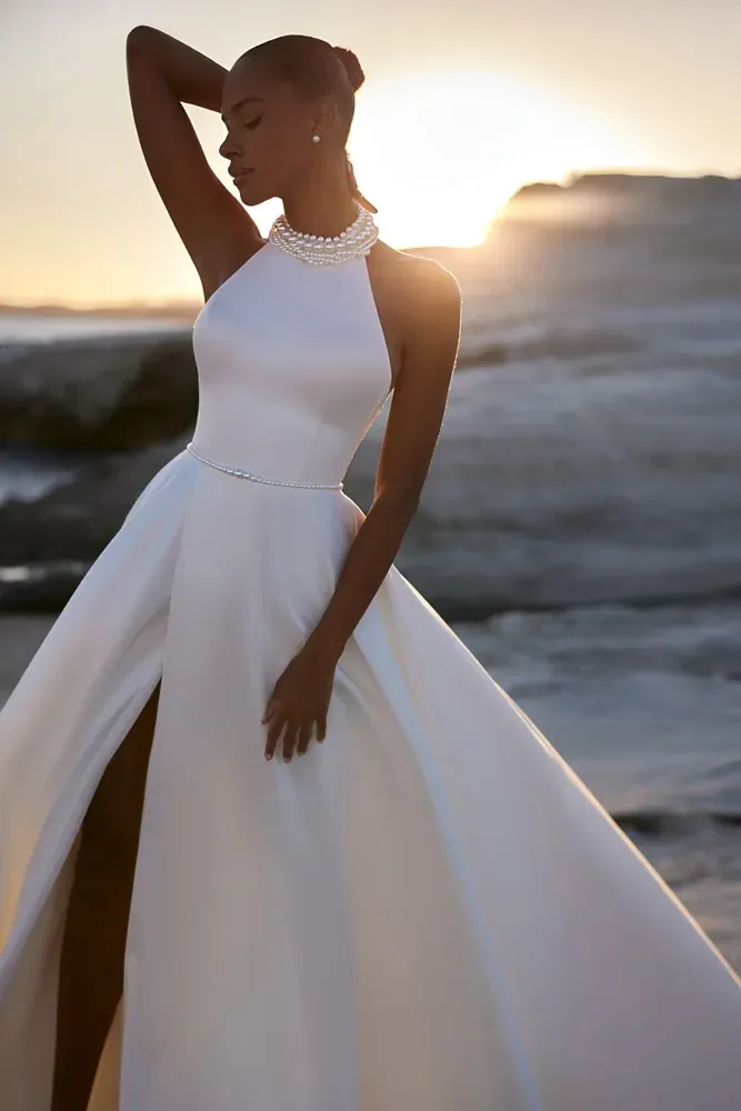 Eine Frau in einem weißen Brautkleid steht an einem Strand.