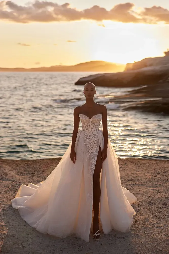 Eine Frau in einem Brautkleid steht an einem Strand in der Nähe des Meeres.