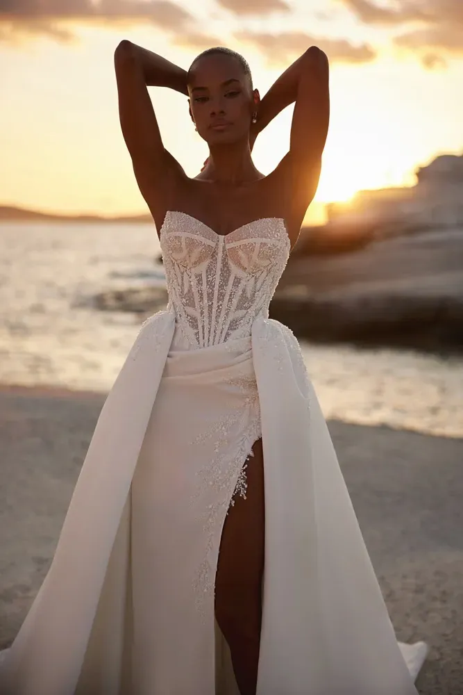 Eine Frau in einem weißen Brautkleid steht an einem Strand.