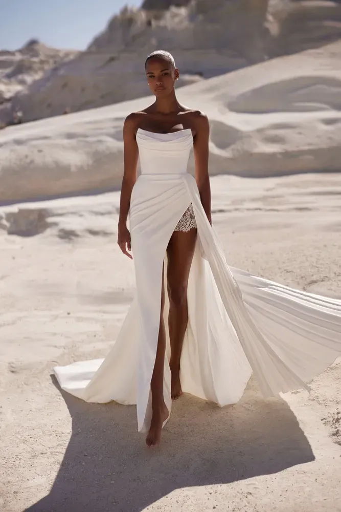 Eine Frau in einem weißen Kleid steht in der Wüste.