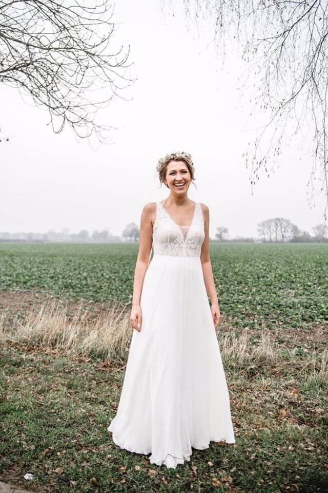 Eine Frau in einem Brautkleid steht auf einem Feld.