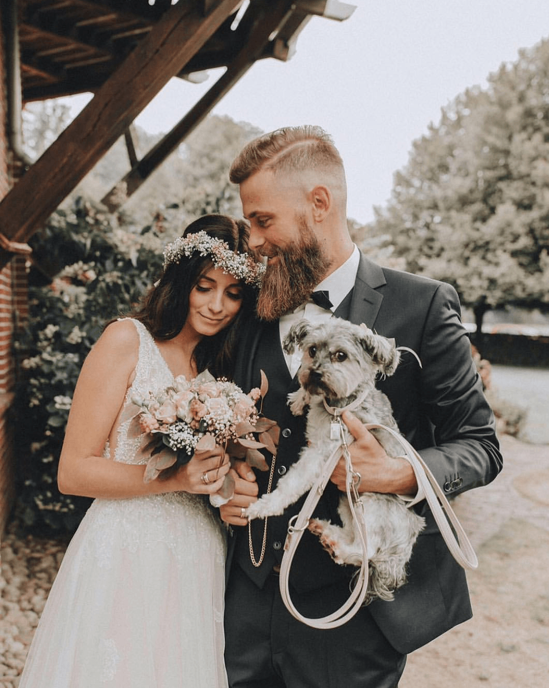 Eine Braut und ein Bräutigam, die einen kleinen Hund an der Leine halten