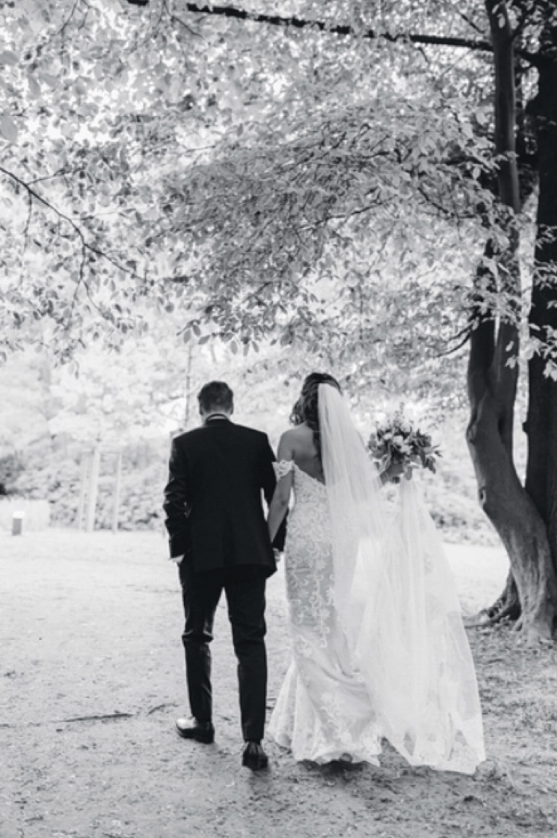 Eine Braut und ein Bräutigam gehen Händchen haltend im Wald spazieren.