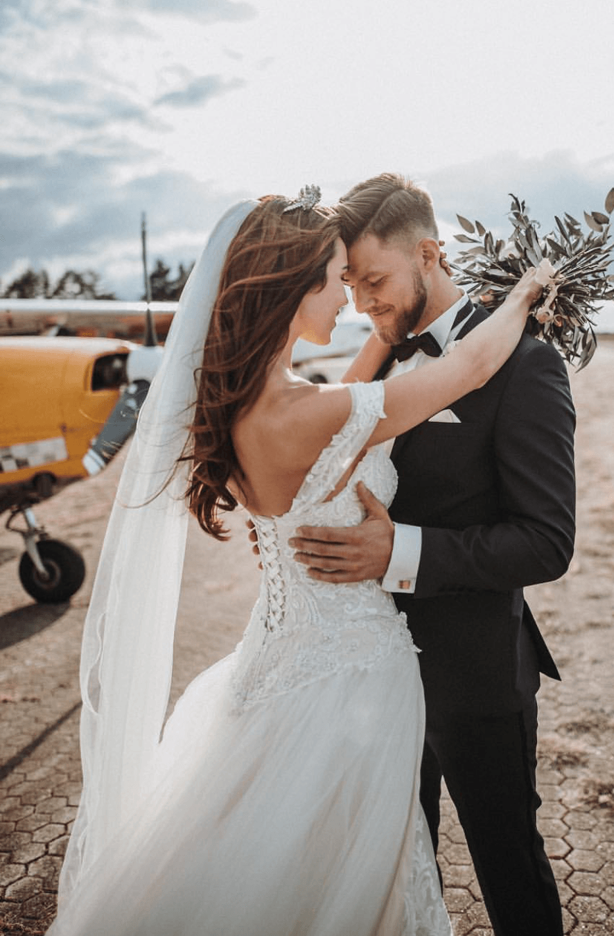 Eine Braut und ein Bräutigam posieren für ein Foto vor einem kleinen Flugzeug.