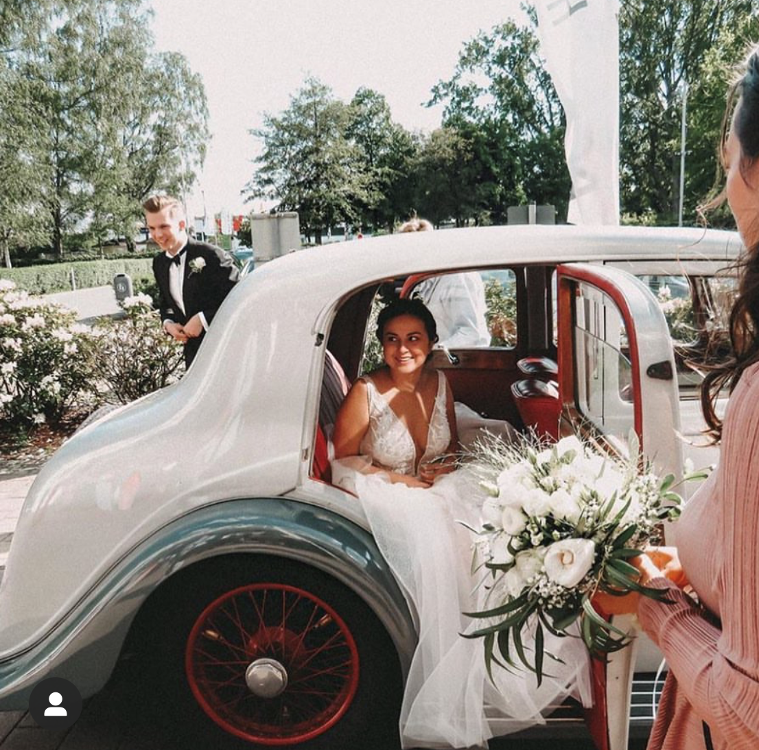 Eine Braut in einem weißen Kleid steigt aus einem weißen Auto