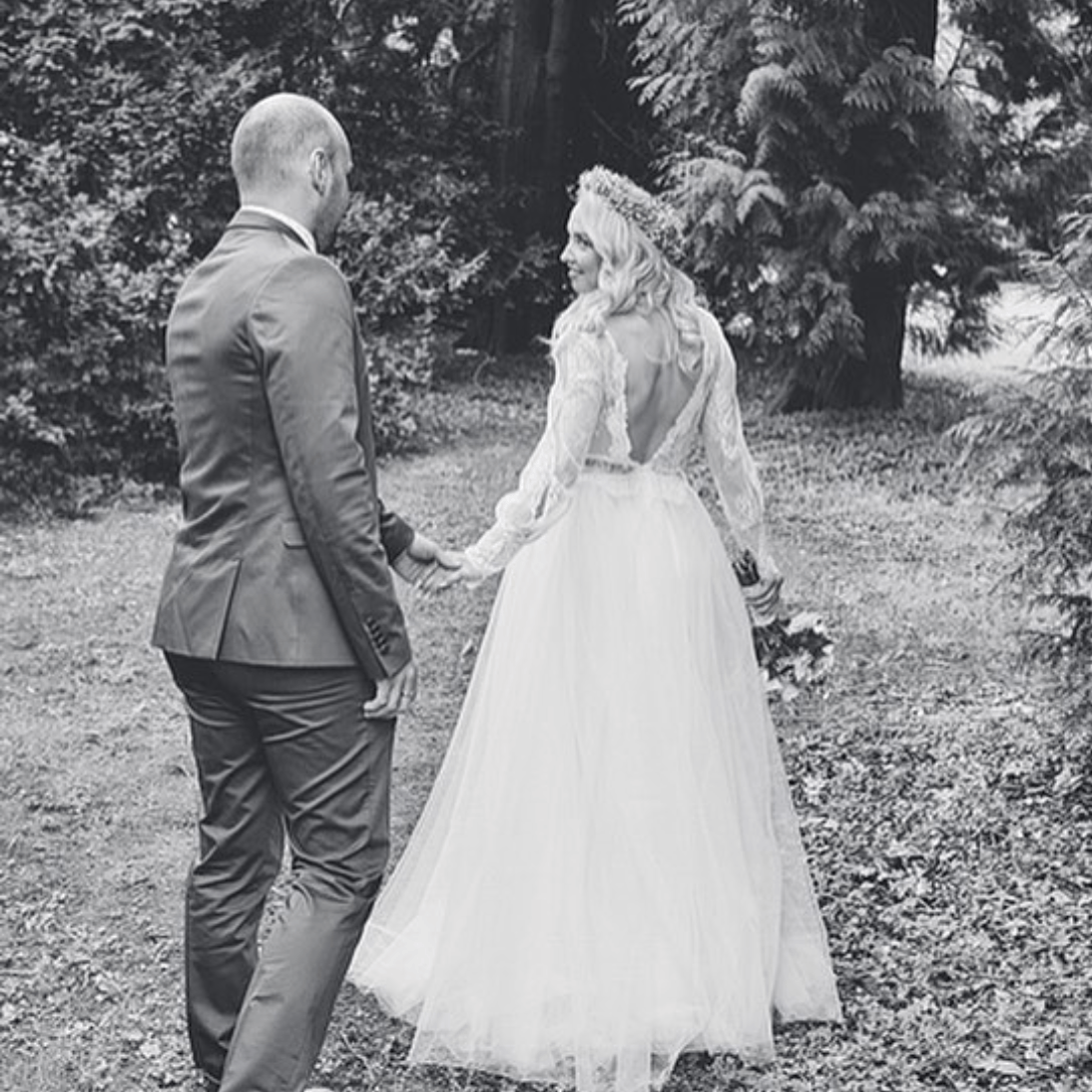 Ein Schwarzweißfoto einer Braut und eines Bräutigams, die Händchen halten.