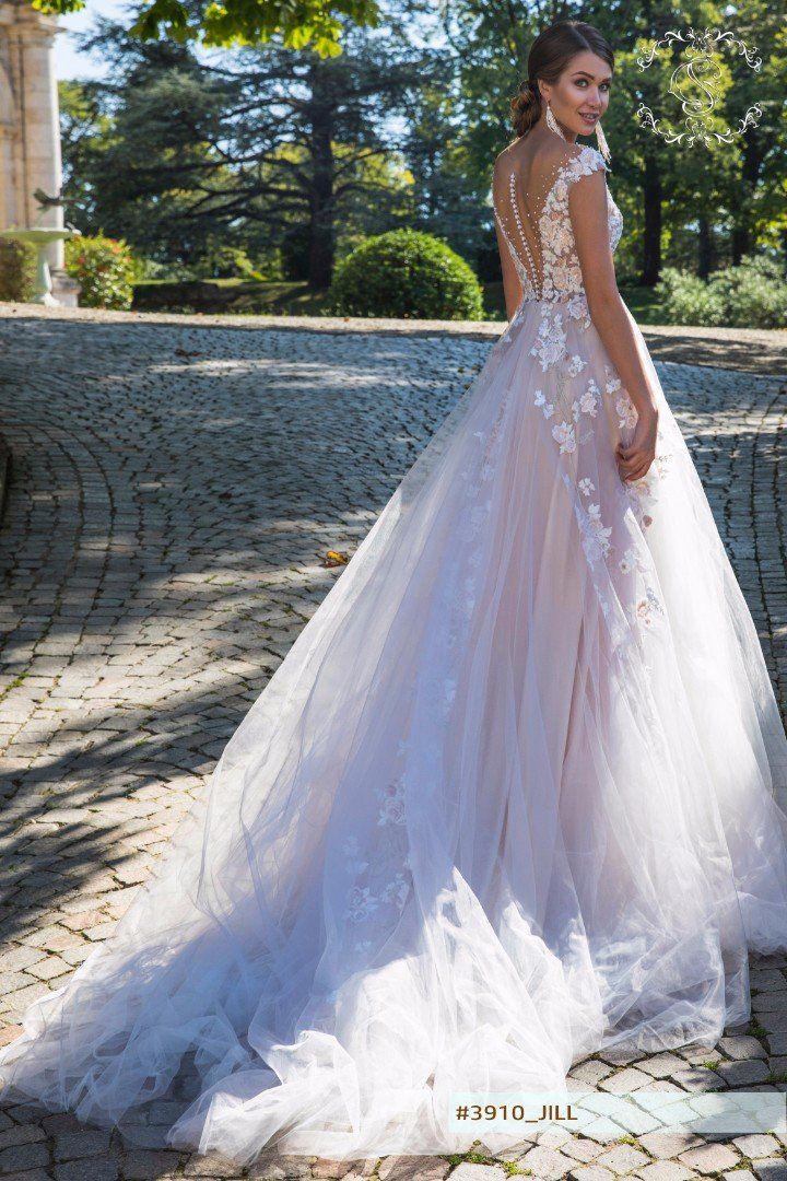 Eine Frau in einem weißen Brautkleid steht vor einem Brunnen.