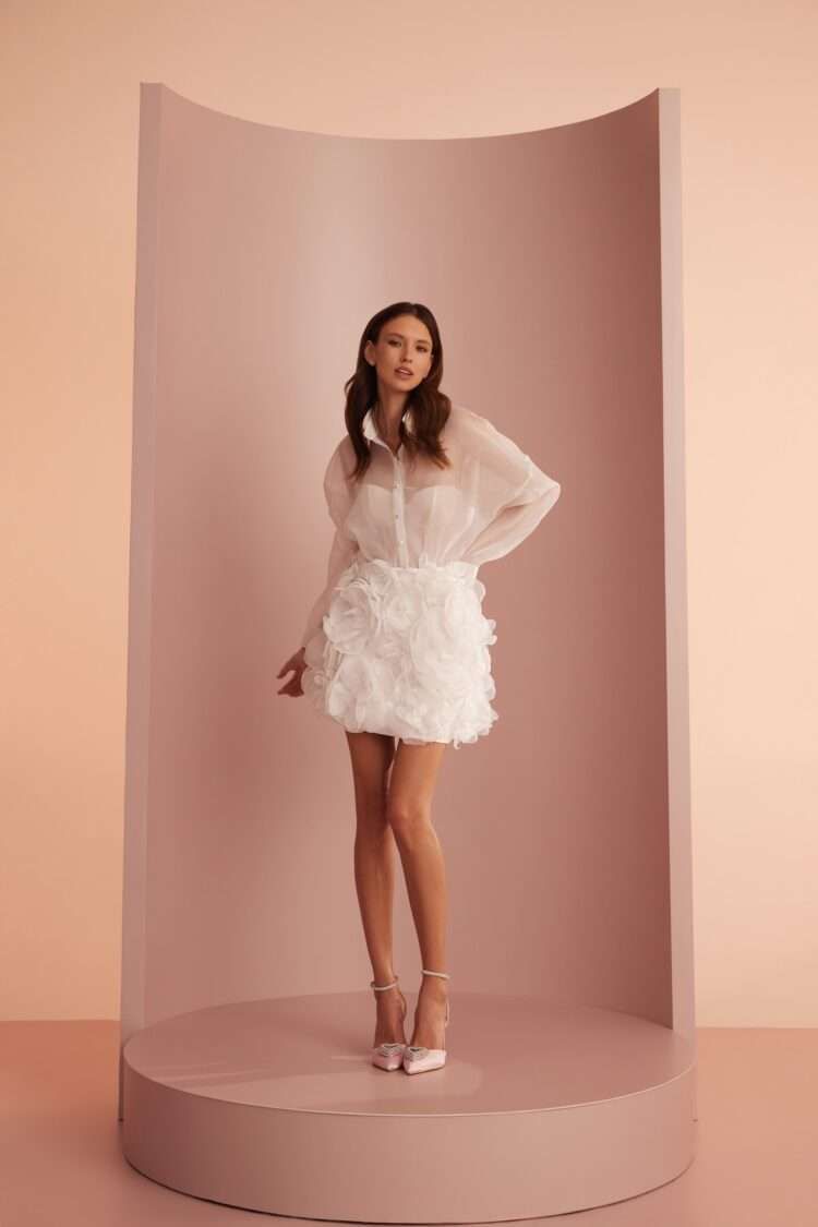 Eine Frau in einem weißen Kleid steht in einem rosa Zimmer.