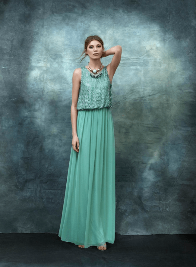 Eine Frau trägt ein langes grünes Kleid und eine Halskette.