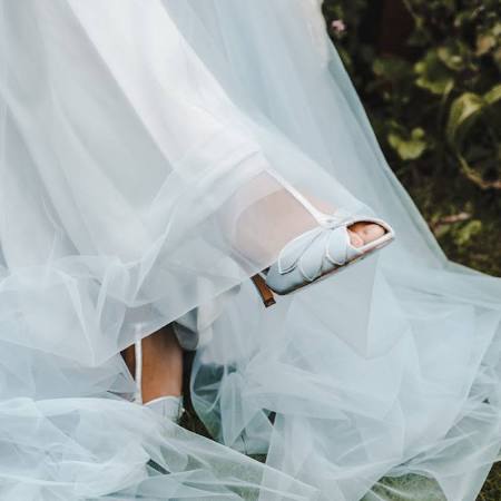 Eine Nahaufnahme einer Person, die ein weißes Kleid und weiße Schuhe trägt.